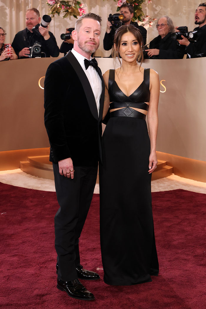 Pareja elegante en alfombra roja con trajes negros destacando outfits de los Globos de Oro que dejaron fans sin palabras.