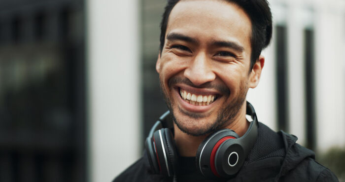 Hombre sonriente con auriculares alrededor del cuello representando momentos de decir no es mi problema y marcharse.