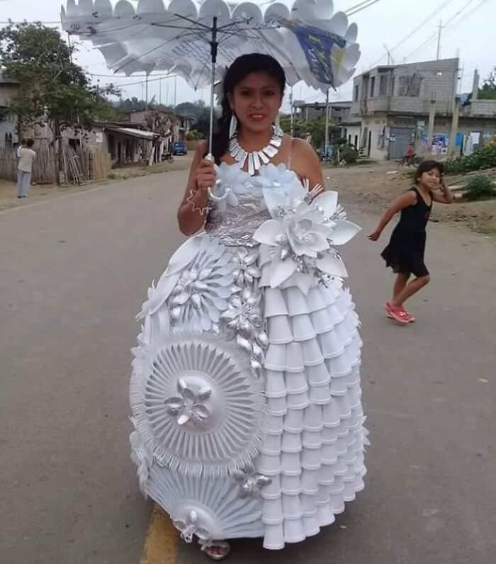 Novia con vestido de boda hecho con vasos y platos desechables en una calle rural, ejemplo de compras cuestionables.