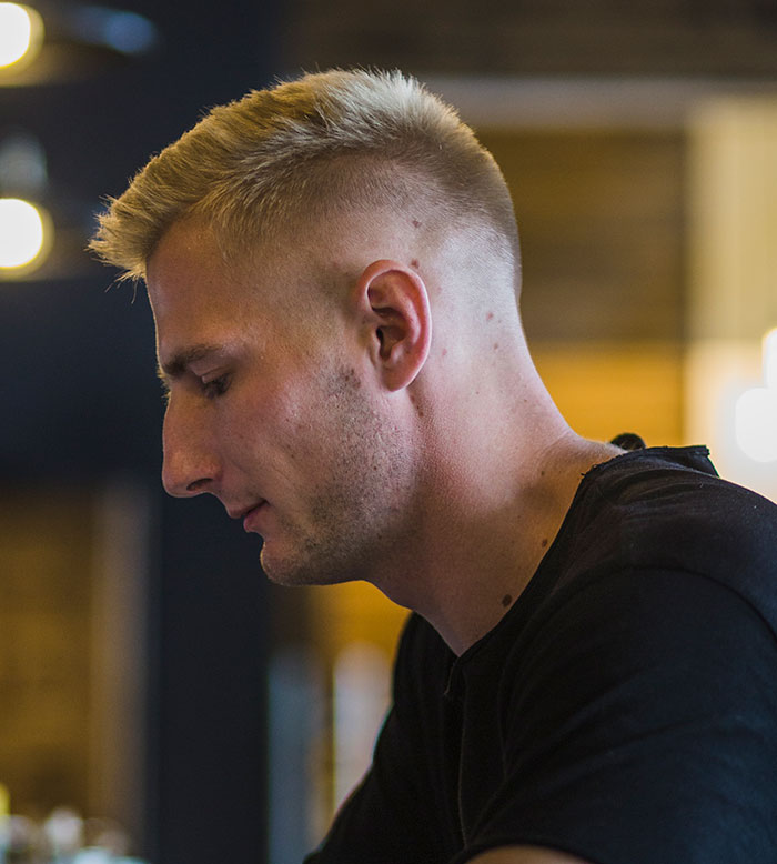 Hombre joven pensando profundamente, mostrando una expresión de concentración e inteligencia en un ambiente interior tenue.