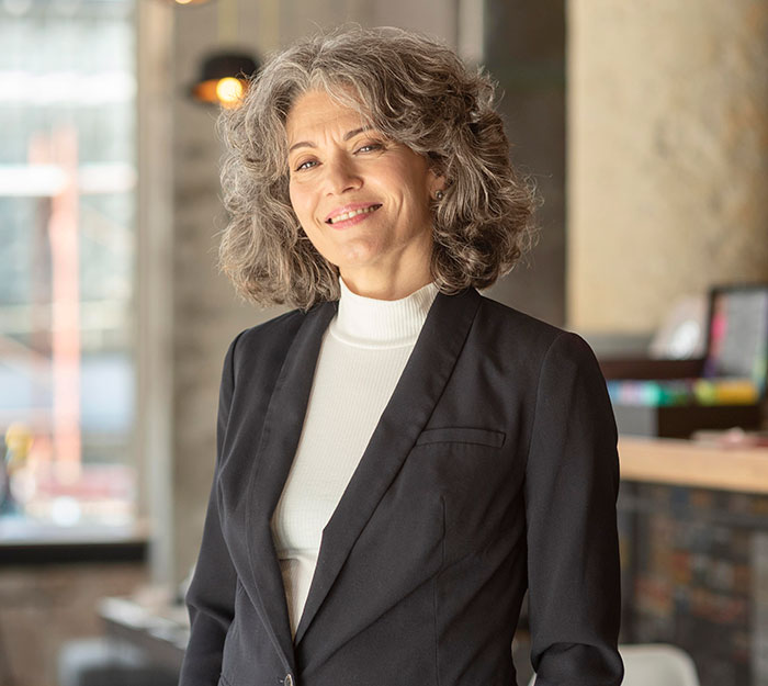 Mujer segura y sonriente en traje formal mostrando inteligencia impresionante en un ambiente profesional moderno.