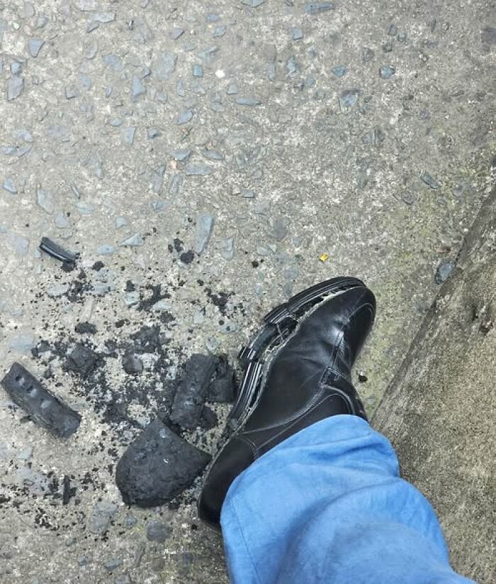 Zapato negro roto en la suela sobre el suelo con restos de carbón, mostrando un día con todo mal.