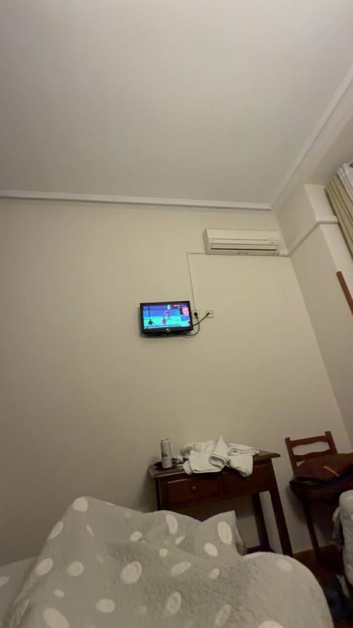 Habitación con televisor pequeño y aire acondicionado, mostrando escena que refleja un día en que todo salió mal.
