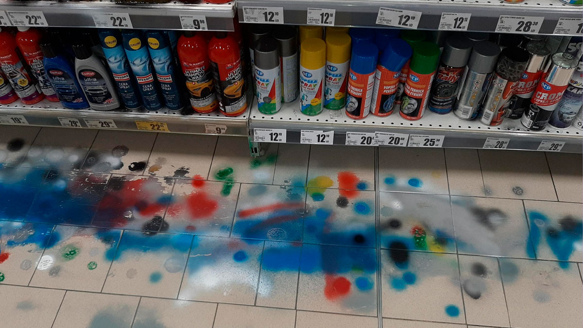 Estantes de tienda con aerosoles y pintura en aerosol derramada en el suelo, ejemplo de personas siendo groseras online.