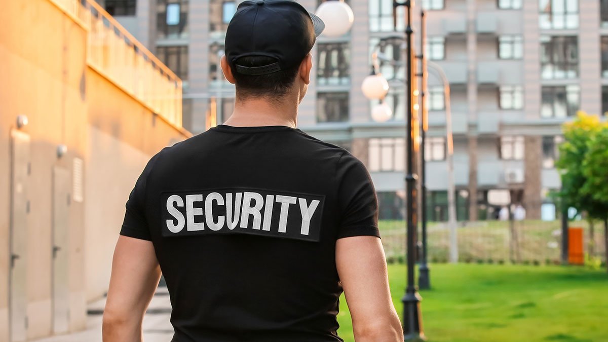 Hombre con camiseta de seguridad mirando hacia un edificio, simbolizando momentos de decir no es mi problema y marcharse.